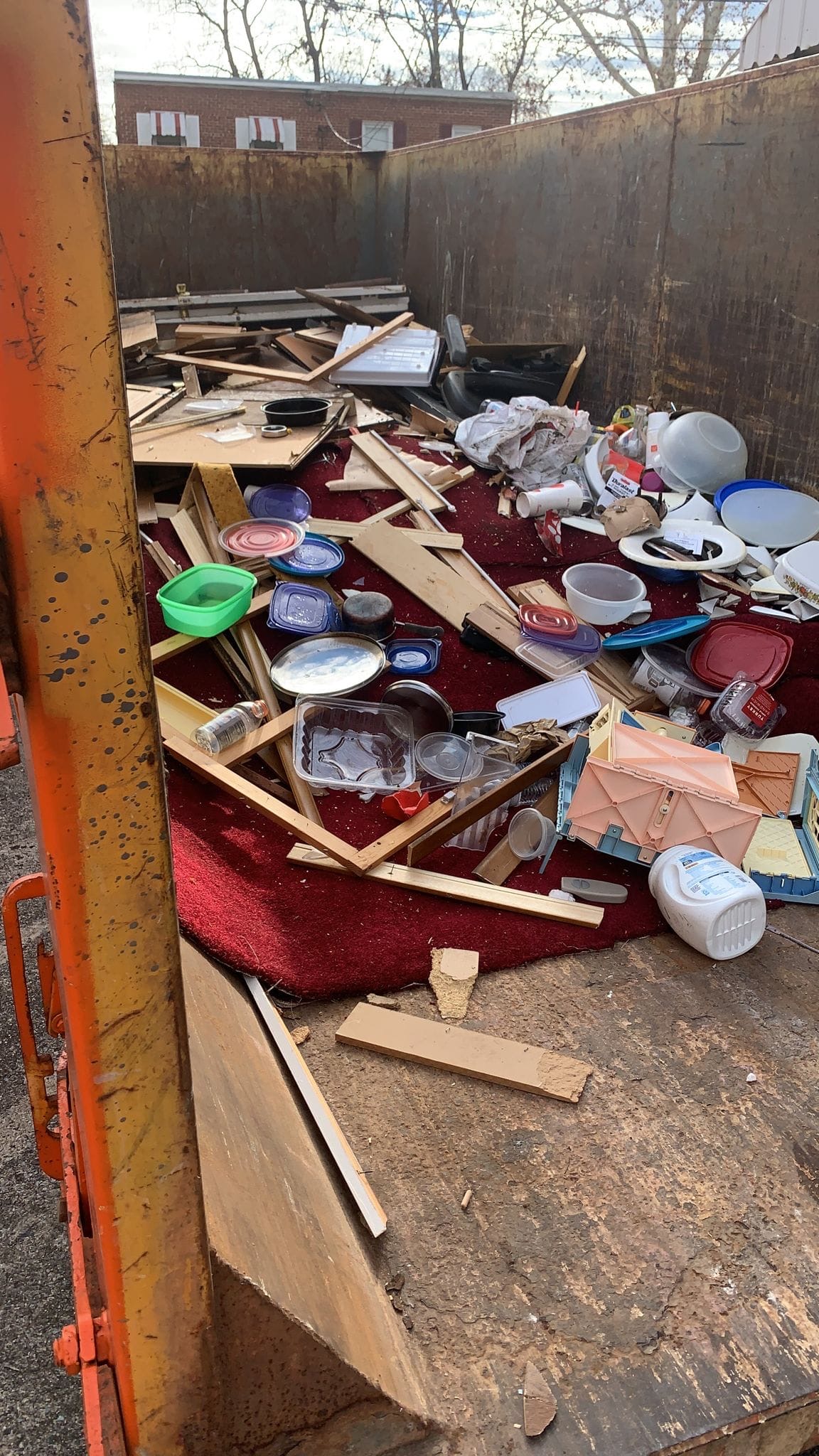 Dumpster packed with carpet, lumber and household debris