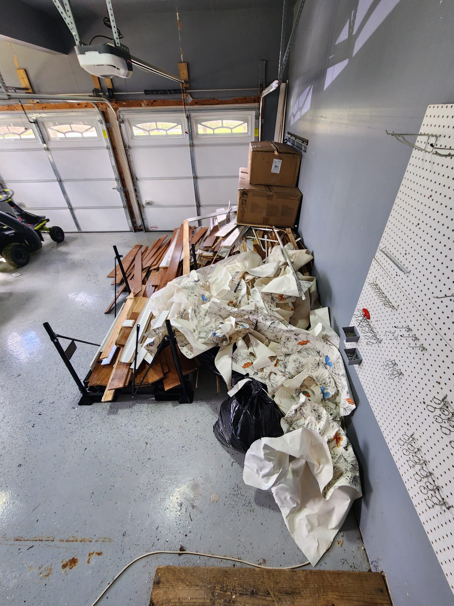 Garage piled with torn-out flooring and wallpaper after a remodel