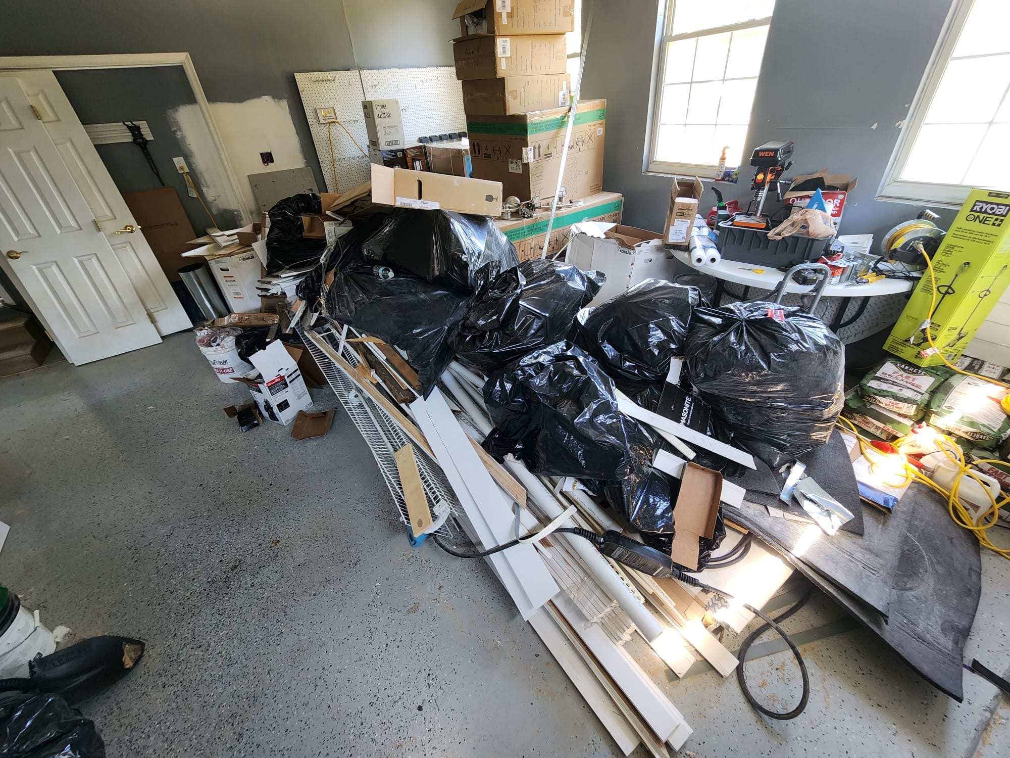 Garage stacked with fixture boxes, trim and renovation debris during an appliance and remodel haul-out